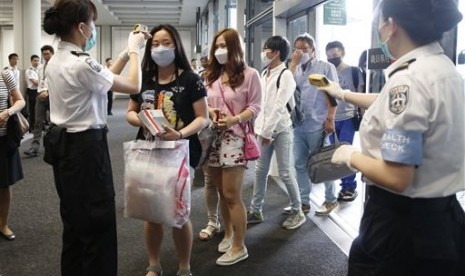 Petugas memeriksa suhu badan para penumpang yang baru tiba dari Busan Korea Selatan, saat mendarat di Bandara Hong Kong, Jumat (5/6), untuk mengantisipasi merebaknya kasus MERS.