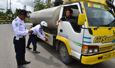 Petugas memeriksa surat kelengkapan mobil truk yang melintas di jalur Pantura Kudus-Semarang di Desa Ngembalrejo, Kudus. Jawa Tengah, Senin (1/3).