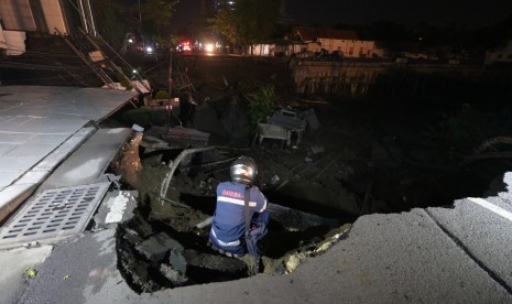 Petugas memeriksa tanah amblas di Kawasan Gubeng Surabaya, Jawa Timur, Selasa (18/12/2018). Petugas masih mencari kemungkinan adanya korban di lokasi jalan amblas yang diduga karena pembangunan gedung dikawasan tersebut.