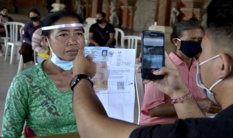 Petugas memotret penerima Bantuan Sosial Tunai (BST) tahap enam di kawasan Batubulan, Gianyar, Bali, Senin (21/9/2020). Kantor Pos Gianyar menyalurkan BST tahap enam senilai Rp300 ribu kepada 39.909 orang Keluarga Penerima Manfaat di empat wilayah kerja yaitu Kabupaten Gianyar, Klungkung, Bangli dan Karangasem untuk membantu meringankan beban ekonomi masyarakat yang terdampak pandemi COVID-19 dengan menerapkan protokol kesehatan yang ketat.