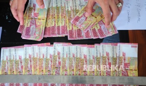 Petugas memperlihatkan barang bukti uang palsu pecahan seratus ribu rupiah.