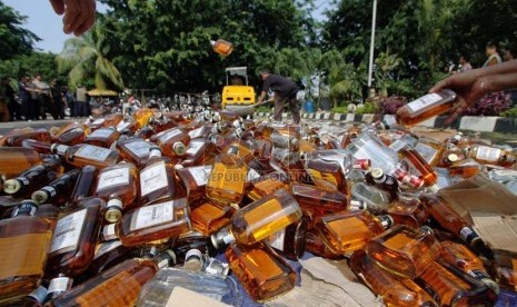   Petugas memusnahkan ratusan botol minuman keras (miras) di halaman Polsek Pulogadung, Jakarta Timur, Jumat (28/2).  (Republika/Yasin Habibi)