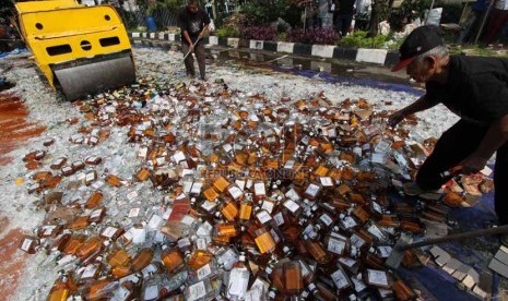   Petugas memusnahkan ratusan botol minuman keras (miras) di halaman Polsek Pulogadung, Jakarta Timur, Jumat (28/2).  (Republika/Yasin Habibi)