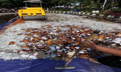   Petugas memusnahkan ratusan botol minuman keras (miras) di halaman Polsek Pulogadung, Jakarta Timur, Jumat (28/2).  (Republika/Yasin Habibi)