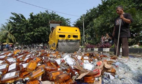   Petugas memusnahkan ratusan botol minuman keras (miras) di halaman Polsek Pulogadung, Jakarta Timur, Jumat (28/2).  (Republika/Yasin Habibi)