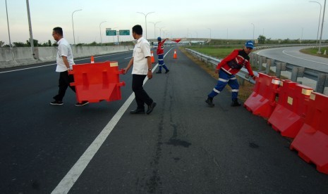 Petugas menata pembatas jalan saat Simulasi pemasangan rambu titik berakhirnya jalur satu arah (one way) di ruas tol KM 262 Pejagan-Pemalang, Brebes, Jawa Tengah. Pemda diminta siapkan jalur alternatif untuk pemudik saat tol diberlakukan satu arah.