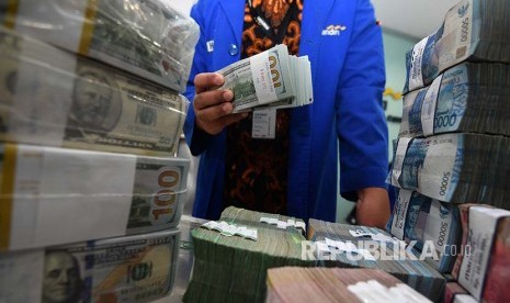 Petugas menata tumpukan uang rupiah dan dolar Amerika di Cash Center Bank Mandiri, Jakarta, Rabu (7/3).Bank Indonesia (BI) mengklaim struktur Utang Luar Negeri (ULN) Indonesia tetap sehat.  