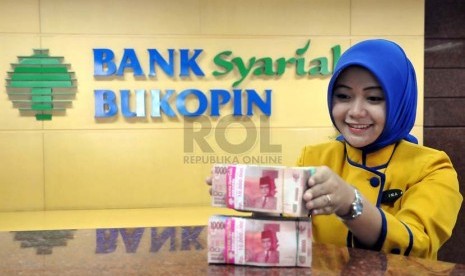 Petugas menata uang nasabah di banking hall salah satu kantor cabang Bank Syariah Bukopin, Jakarta, Senin (25/8).(Republika/Prayogi)