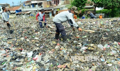 Petugas mencangkul sampah yang sudah bercampur dengan tanah di lahan kosong RT 03 RW, Kelurahan Cibangkong, Kecamatan Batununggal, Kota Bandung, Kamis (6/7)