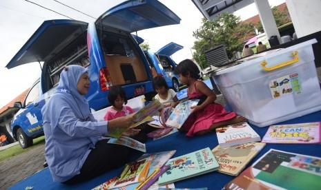 Petugas mendampingi sejumlah anak eks anggota Gerakan Fajar Nusantara (Gafatar) membaca buku di perpustakaan keliling di penampungan Asrama Transito Jawa Timur, Surabaya, Jawa Timur, Senin (25/1).