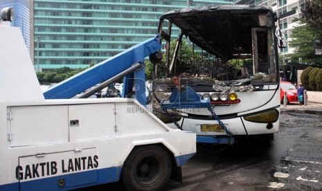 Petugas menderek bangkai bus bernopol B 7021 IW yang terbakar di kawasan Bundaran HI, Jakarta Pusat, Senin (16/12).  (Republika/Yasin Habibi)