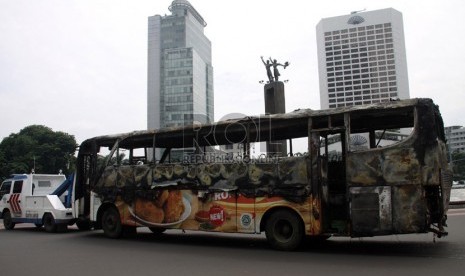 Petugas menderek bangkai bus bernopol B 7021 IW yang terbakar di kawasan Bundaran HI, Jakarta Pusat, Senin (16/12).  (Republika/Yasin Habibi)