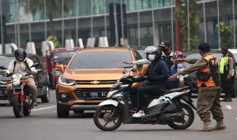  Petugas mengalihkan pengendara motor yang akan masuk ke Surabaya saat penyekatan PPKM Darurat, di Bundaran Waru, Surabaya, Jawa Timur. 