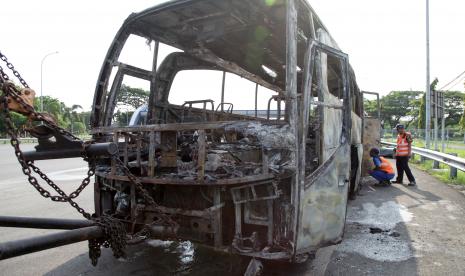 Petugas mengamati bus pariwisata yang habis terbakar.