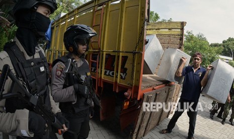 Petugas mengangkat kotak suara berisi logistik Pilkada Kota Madiun dan Pilgub Jatim yang didistribusikan di kawasan Nambangan Kidul, Madiun, Jawa Timur, Senin (25/6). 