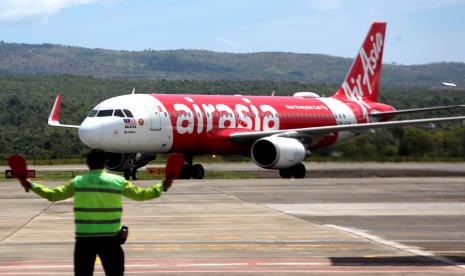 Petugas mengarahkan pesawat maskapai penerbangan Air Asia.