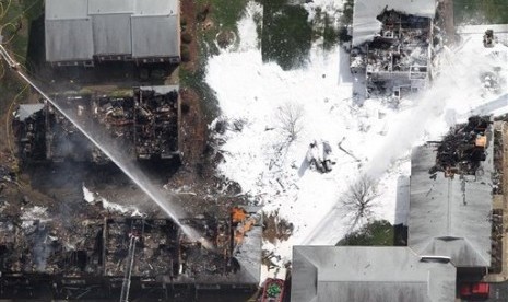 Petugas  mengatasi kebakaran apartemen akibat hantaman jet tempur Angkatan Laut AS yang jatuh di Virginia Beach, Jumat (6/4) waktu setempat.