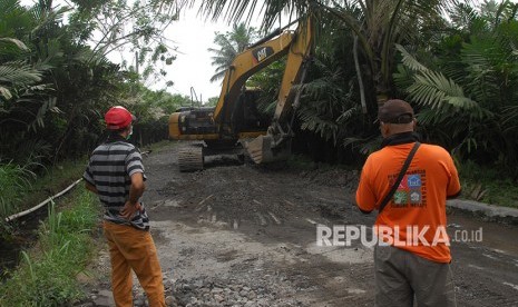 Petugas mengawasi ekskavator yang tengah melakukan perbaikan jalur evakuasi di kawasan lereng Gunung Merapi Desa Kaliurang, Srumbung, Magelang, Jawa Tengah, Senin (21/5).