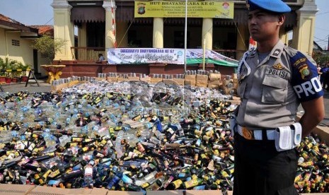  Petugas mengawasi ribuan botol minuman keras dan kepingan DVD porno hasil penertiban di halaman Polsek Metro Palmerah, Jakarta Barat, Senin (8/7).  (Republika/Prayogi)