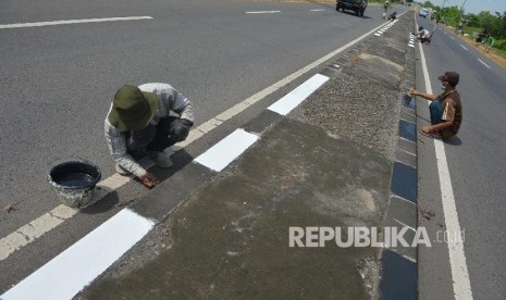 Petugas mengecat trotoar di Jalur Pantura Kawasan Lohbener, Indramayu, Jawa Barat, Senin (20/6). (Republika/Raisan Al Farisi)