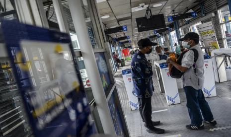 Petugas mengecek sertifikat vaksin milik calon penumpang di Halte Transjakarta Harmoni, Jakarta.