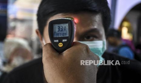 Petugas mengecek suhu tubuh calon penumpang menggunakan thermo gun di Stasiun Bandung, Kota Bandung, Ahad (15/3). 