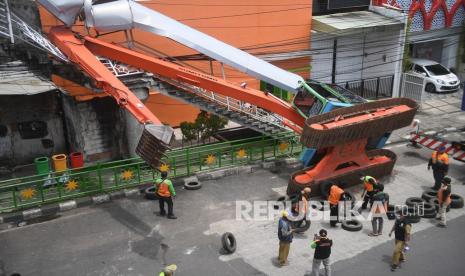 Petugas mengevakuasi ekskavator yang terguling menimpa tangga jembatan penyeberangan orang (JPO) di Kampung Melayu, Jakarta, Selasa (22/9/2020). Ekskavator milik Dinas Lingkungan Hidup (DLH) DKI Jakarta itu terguling dari atas mobil mobilisasi saat akan dikembalikan ke gudang.