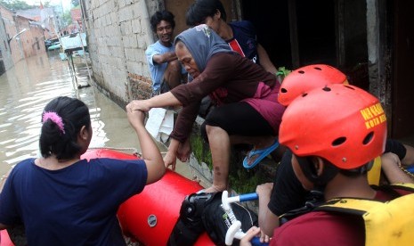 Petugas mengevakuasi sejumlah warga dengan perahu karet saat banjir merendam kawasan penduduk Kartini, Margahayu, Bekasi, Jawa Barat, Minggu (28/2).