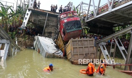 Petugas mengevakuasi truk di lokasi jembatan Widang yang runtuh, Tuban, Jawa Timur, Selasa (17/4). 