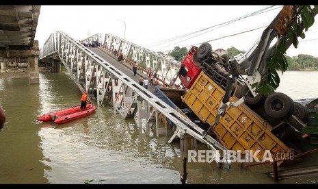 Petugas mengevakuasi truk di lokasi jembatan Widang yang runtuh, Tuban, Jawa Timur, Selasa (17/4). Sisi barat jembatan itu runtuh sekitar 50 meter dan mengakibatkan satu pengemudi truk meninggal dunia, dan melukai tiga korban lainnya, sementara tiga truk dan sebuah sepeda motor masuk ke Bengawan Solo. 