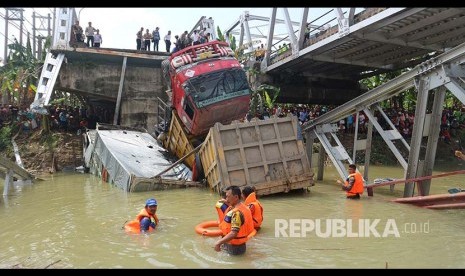 Petugas mengevakuasi truk di lokasi jembatan Widang yang runtuh, Tuban, Jawa Timur, Selasa (17/4). Sisi barat jembatan itu runtuh sekitar 50 meter dan mengakibatkan satu pengemudi truk meninggal dunia, dan melukai tiga korban lainnya, sementara tiga truk dan sebuah sepeda motor masuk ke Bengawan Solo. 