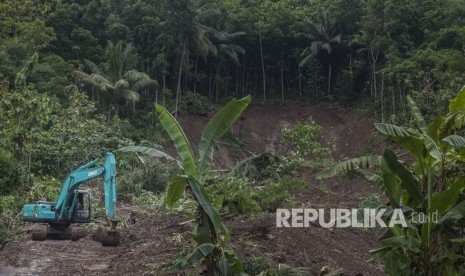 Petugas menggunakan alat berat guna membersihkan material longsor yang menutup akses jalan di kawasan di Pendoworejo, Girimulyo, Kulonprogo, DI Yogyakarta, Kamis (30/11). 