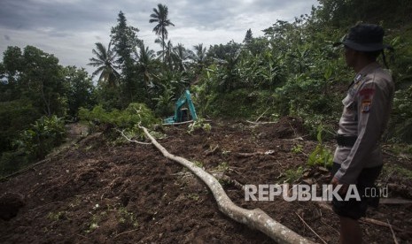 Petugas menggunakan alat berat guna membersihkan material lonsor yang menutup akses jalan di kawasan di Pendoworejo, Girimulyo, Kulonprogo, DI Yogyakarta, Kamis (30/11). 