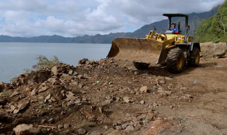 Petugas menggunakan alat berat untuk membersihkan material longsoran bukit akibat gempa bumi Karangasem Bali yang menutup jalan di kawasan Kintamani, Bangli, Bali, Minggu (17/10/2021). Hingga Minggu (17/10) petang, ratusan KK yang tinggal di beberapa desa di wilayah Kecamatan Kintamani seperti Desa Trunyan masih terisolir karena sejumlah titik di satu-satunya akses jalur darat yang menghubungkan wilayah desa mereka menuju Kota Bangli masih tertimbun material longsor akibat gempa bumi 4,8 SR pada Sabtu (16/10) dini hari.