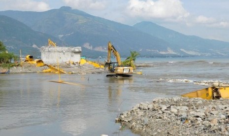 Petugas menggunakan alat berat untuk meratakan sisa reruntuhan puing Jembatan Palu IV atau jembatan kuning , di Palu Kamis (8/11)