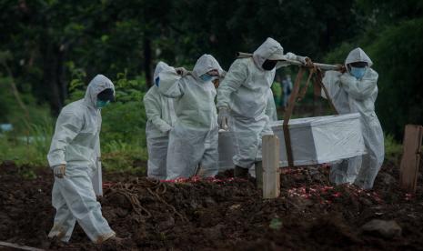 Petugas menggunakan pakaian alat pelindung diri (APD) saat memakamkan jenazah pasien Covid-19 di TPU Srengseng Sawah, Jagakarsa, Jakarta.