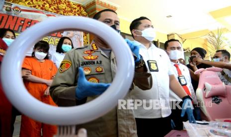 Petugas menghadirkan tersangka berinisial RR (kiri) dan menunjukkan barang bukti kasus pornografi saat konferensi pers di Polresta Denpasar, Bali, Senin (20/9/2021). Petugas Polresta Denpasar menangkap tersangka RR yang melakukan tindakan pornoaksi dan disiarkan secara langsung melalui akun Kuda Poni di platform 