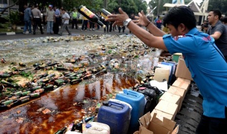 Petugas menghancurkan botol-botol miras hasil sitaan di halaman Polres Jakarta Selatan, Rabu (10/6).(Republika/Wihdan Hidayat)