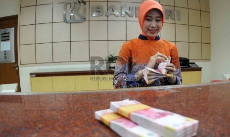  Petugas menghitung uang di banking hall Bank Rakyat Indonesia, Jakarta, Selasa (20/10).