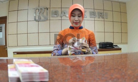 Petugas menghitung uang di banking hall Bank Rakyat Indonesia, Jakarta, Selasa (20/10).