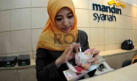  Petugas menghitung uang di banking hall Bank Syariah Mandiri, Jakarta, baru-baru ini.. 