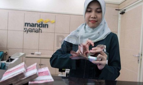 Petugas menghitung uang nasabah di banking hall salah satu kantor cabang Bank Syariah Mandiri, Jakarta, Jumat (4/7).  (Republika/Adhi Wicaksono)