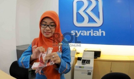 Petugas menghitung uang nasabah di salah kantor Bank BRI Syariah, Jakarta, Kamis (20/8).