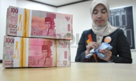 Petugas menghitung uang nasabah di salah satu kantor cabang bank syariah di Jakarta.(Prayogi/Republika)