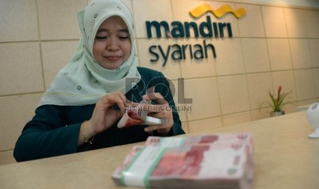 Petugas menghitung uang nasabah di salah satu kantor cabang Bank Syariah Mandiri, Jakarta, Kamis (21/5). 