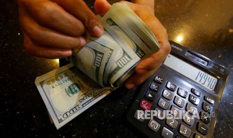 Petugas menghitung uang pecahan dolar Amerika Serikat di gerai penukaran mata uang asing. Nilai tukar dolar AS terhadap mata uang utama dunia melemah. 