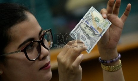 Petugas menghitung uang pecahan Dolar AS di salah satu tempat penukaran uang, Jakarta, Senin (2/2).(Republika/Prayogi)