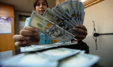 Petugas menghitung uang pecahan Dolar AS di salah satu tempat penukaran uang, Jakarta, Senin (2/2).(Republika/Prayogi)