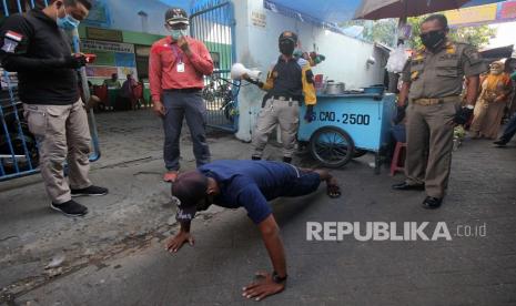 Petugas menghukum warga yang tidak memakai masker untuk 