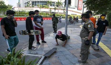 Petugas menghukum warga yang tidak memakai masker untuk 